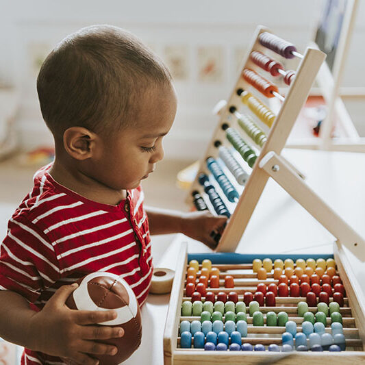Kid playing with a colorful wooden abacus